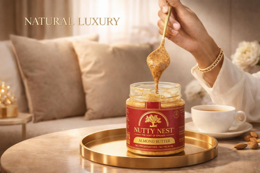 Person scooping Nutty Nest Almond Butter from a jar on a gold tray with a cup of coffee in the background.